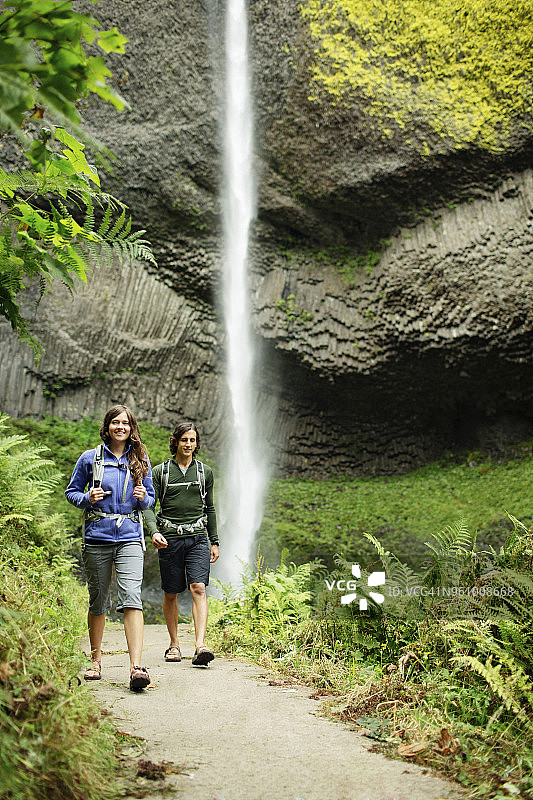 一对夫妇在森林瀑布旁的小径上散步图片素材