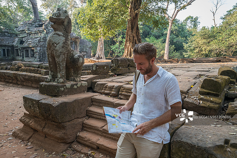 一名年轻人在柬埔寨参观吴哥窟的庙宇并阅读路线图图片素材