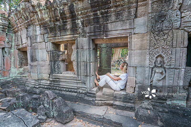 美丽的女孩坐在古庙的窗户上，思考和欣赏柬埔寨建筑的氛围;人们旅游亚洲年轻的女游客图片素材