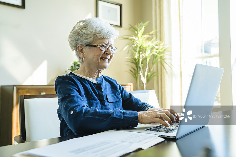 在家里用笔记本电脑时，老妇人微笑着图片素材