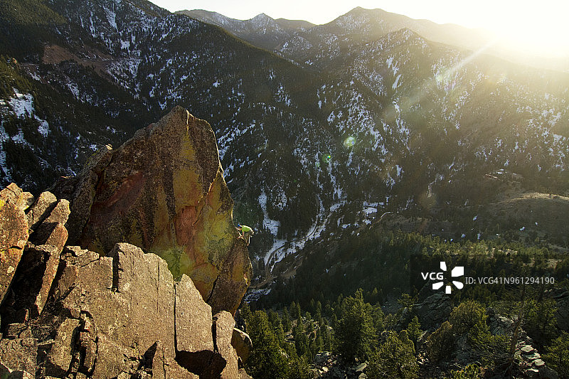 一个人在阳光明媚的日子里爬岩石山图片素材