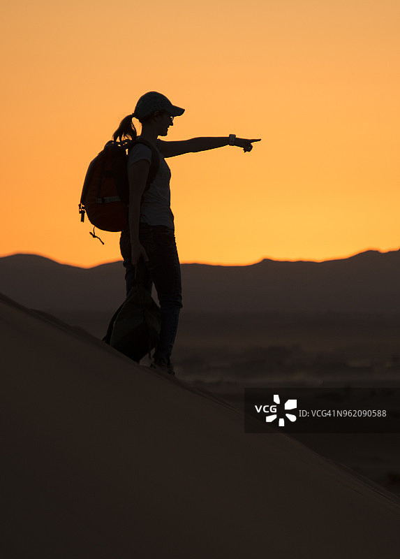 年轻的女子在撒哈拉沙漠日落，享受美丽的自然和指向山脉，Mergouga，摩洛哥图片素材