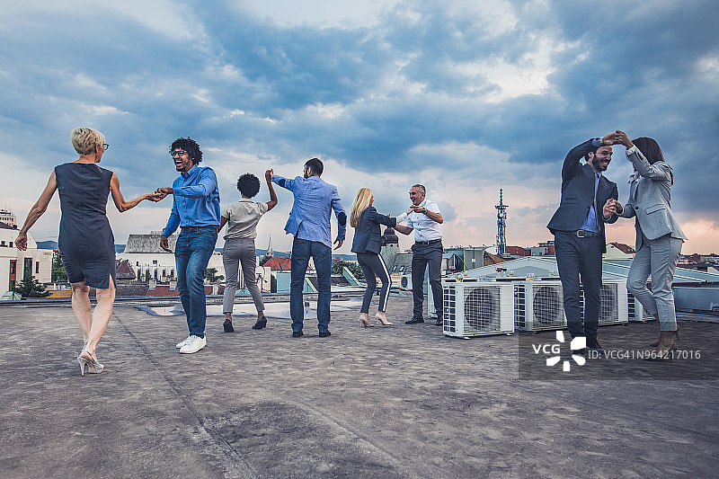 商业伙伴们在屋顶派对上尽情跳舞。图片素材