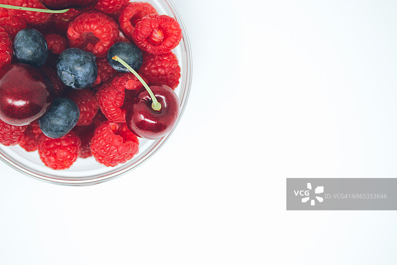 覆盆子，蓝莓和樱桃放在一个玻璃碗里图片素材