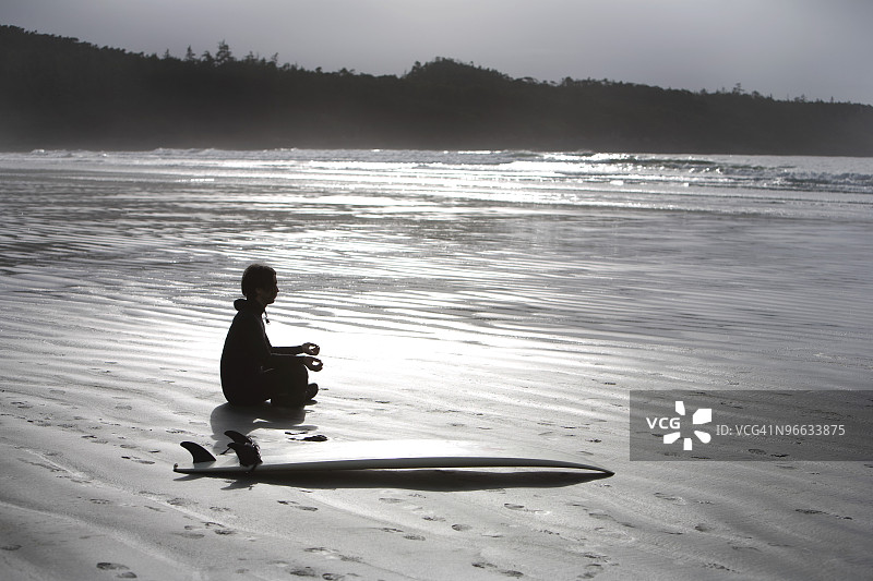 冲浪者在海滩上冥想，加拿大不列颠哥伦比亚省托菲诺附近的考克斯湾图片素材