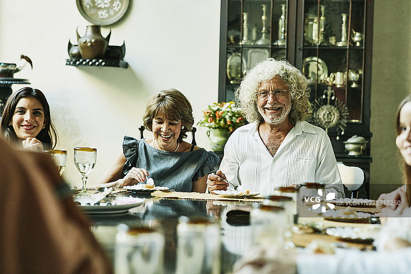 在家庭生日宴会上，微笑的祖父母坐在餐桌前吃蛋糕的肖像图片素材