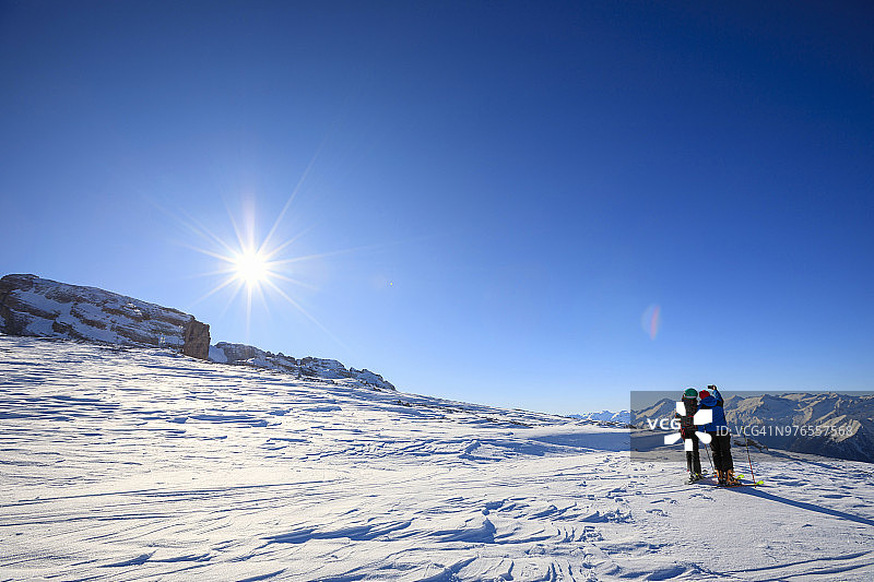 有问题。一对年轻的女人和一个男人在阳光明媚的滑雪胜地使用智能手机滑雪业余冬季运动。高山雪景。意大利阿尔卑斯山脉的白云石圣母迪坎皮里奥，意大利。图片素材