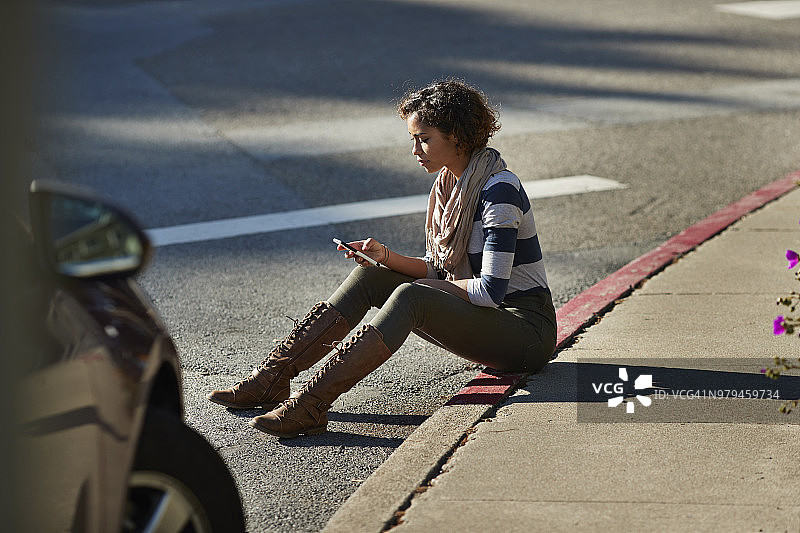 坐在路边看手机的女人图片素材