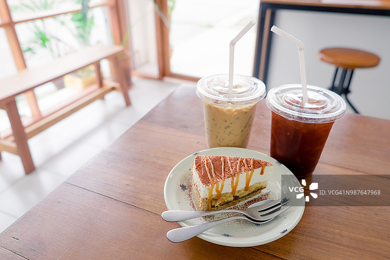 咖啡馆的木桌上放着冰咖啡和蛋糕。图片素材