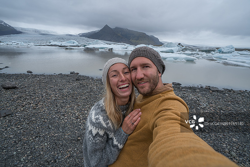 年轻夫妇与冰川泻湖自拍，冰山浮在水上图片素材