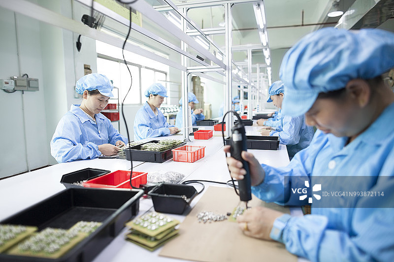 中国东莞一家LED照明工厂，工人们穿着制服图片素材