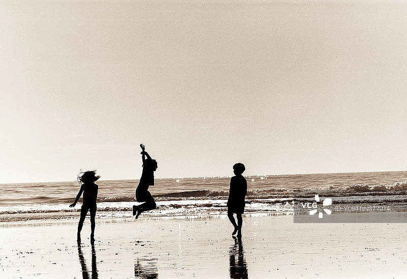 三个孩子在海滩上玩耍图片素材