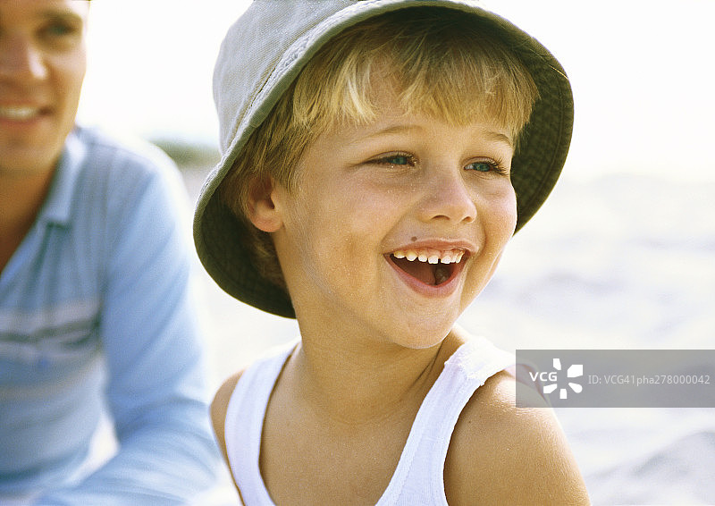男孩戴着帽子和父亲在海滩上图片素材