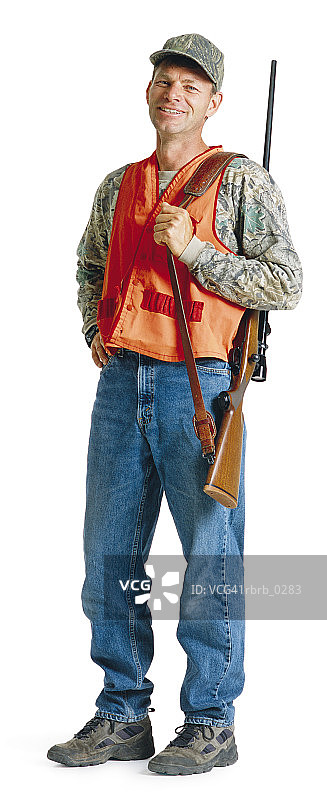 一名身穿牛仔裤和橙色背心的白人男子戴着一顶帽子，肩上挎着步枪背带图片素材