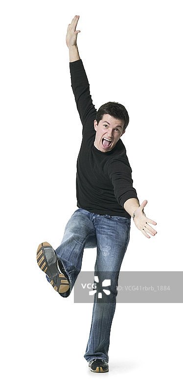 全身拍摄的一个年轻的成年男子在黑色的衬衫，因为他开玩笑地跳舞图片素材