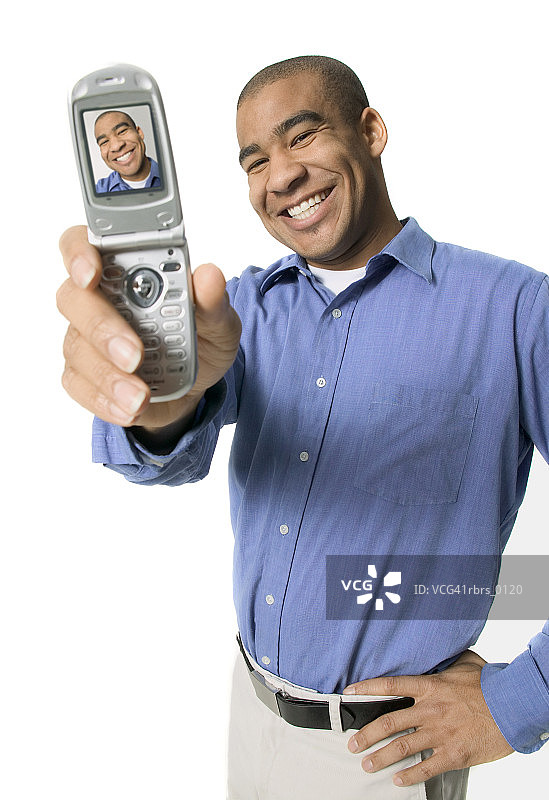 一个年轻的成年男子微笑着对着他的照相手机图片素材