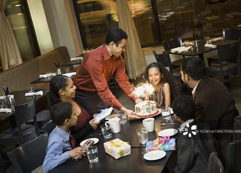 晚餐时，服务生为女孩(10-11)带来生日蛋糕图片素材