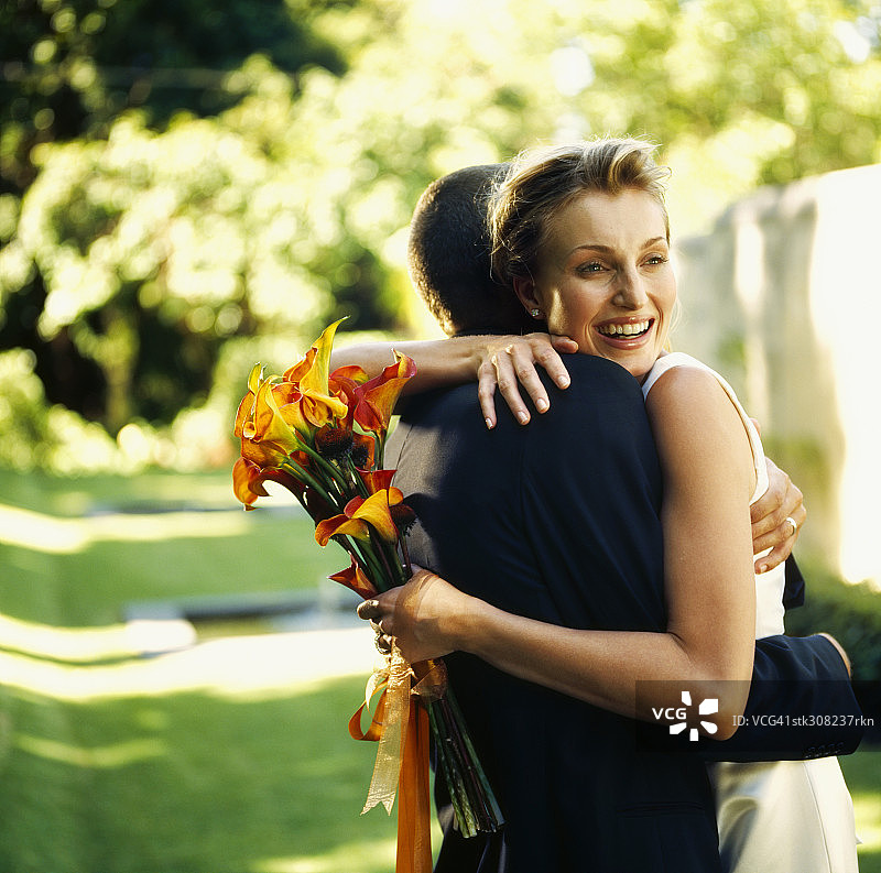 一对新婚夫妇在草坪上拥抱对方的侧影图片素材