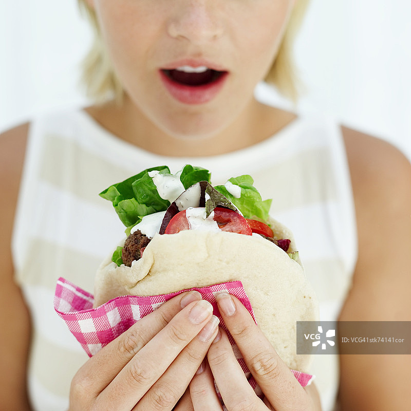 一个女人拿着皮塔饼面包三明治的特写镜头图片素材