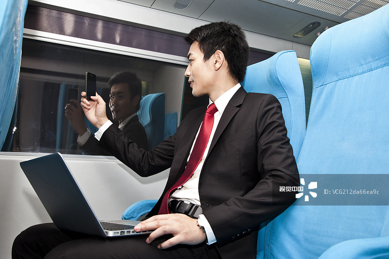 年轻商务男士在车厢内使用笔记本电脑图片素材
