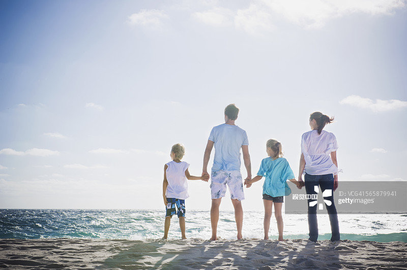 白人父母和孩子手牵着手在海滩上图片素材