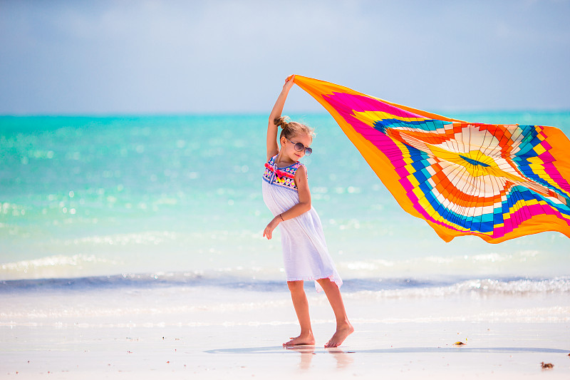 快乐的年轻女孩戴着太阳镜和毛巾对着大海图片下载