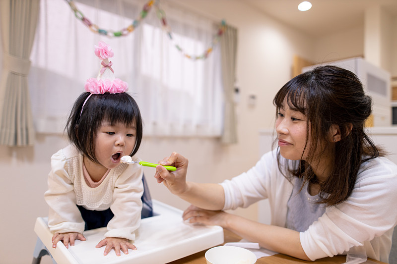 年轻的母亲给她的宝贝女儿喝酸奶图片素材