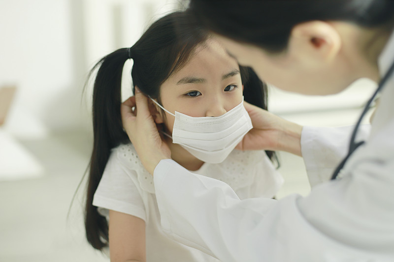 医生给女孩戴上流感口罩图片素材
