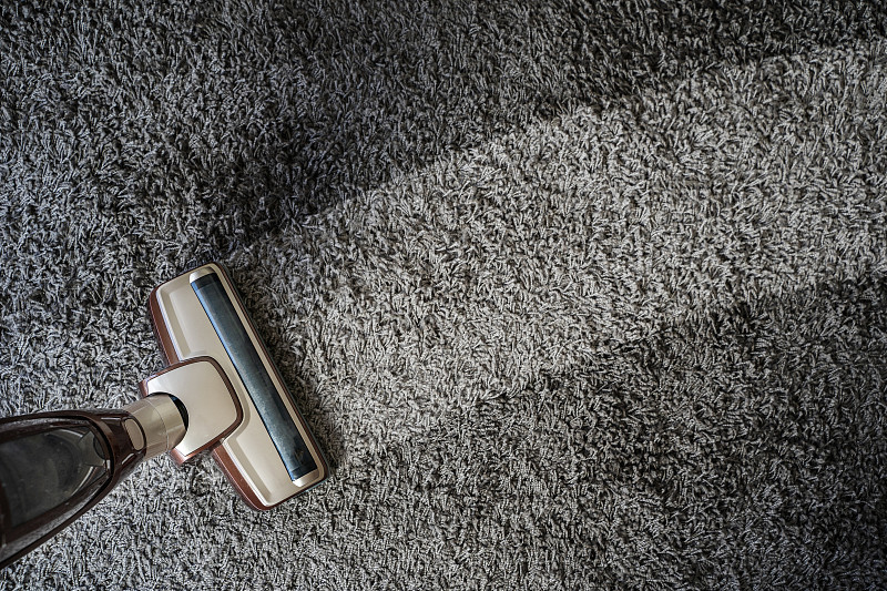 高角度的吸尘器清洁地毯在家里图片下载
