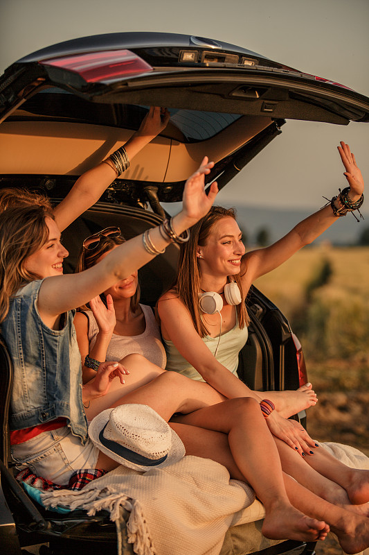 快乐的年轻女性在她们的露营之旅在远处挥手图片下载