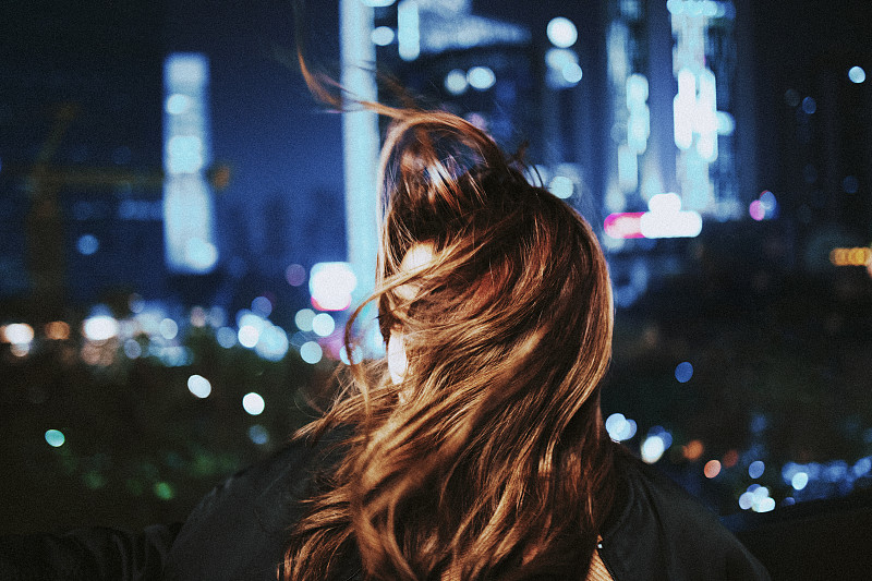 夜晚的城市里，年轻美丽的卷发女子图片下载
