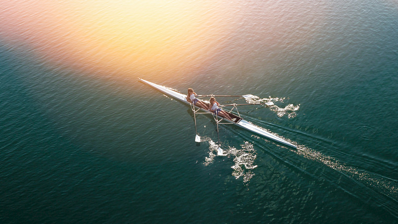两名女运动员在阳光下在湖上划船图片下载