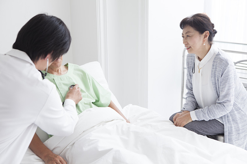 一位医生告诉一位住院的老人病情。一个在旁边倾听的妻子。图片下载