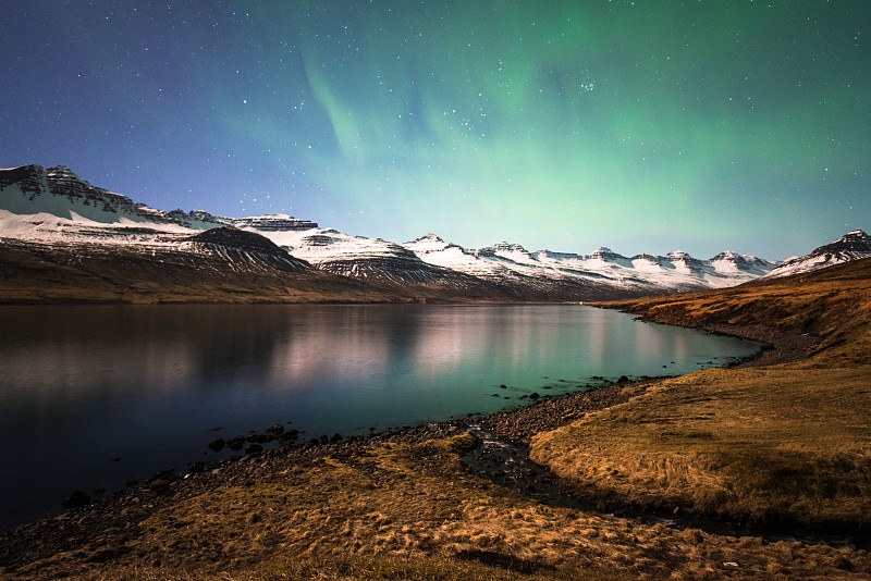 北极光在Stöðvarfjörður的山脉上，这个小镇位于冰岛的东峡湾。图片素材
