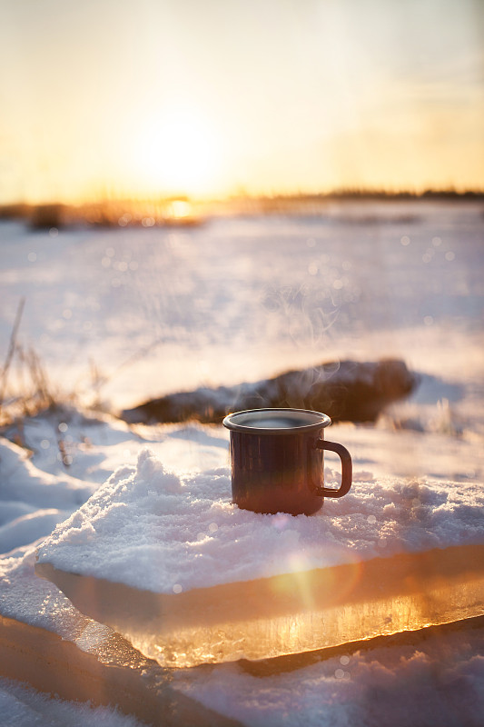 一杯热腾腾的咖啡上了雪，背景是冬日阳光明媚的日子图片下载