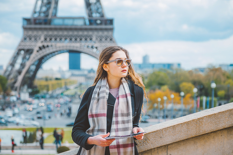 年轻的女游客拿着巴黎的地图和埃菲尔铁塔比拼图片素材