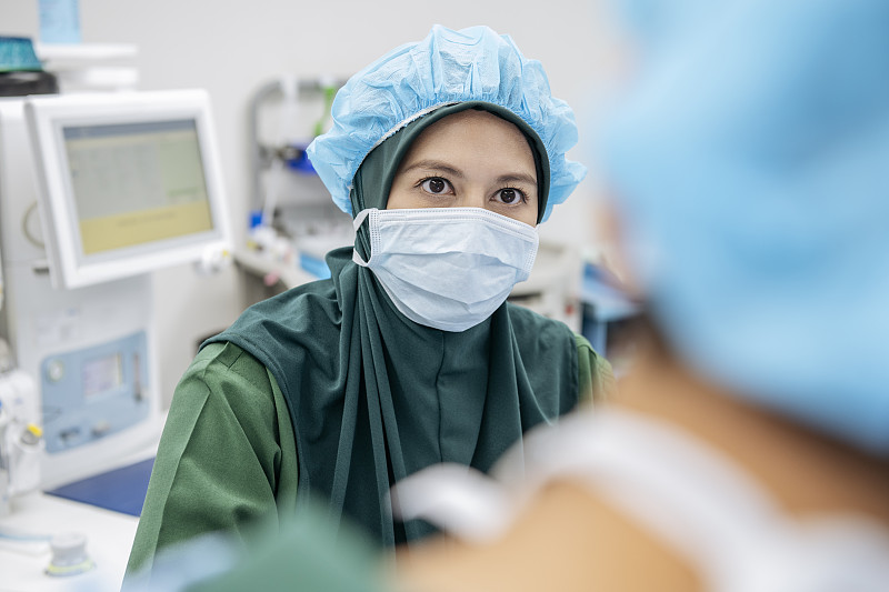 马来西亚医生戴着外科口罩，表情严肃图片下载