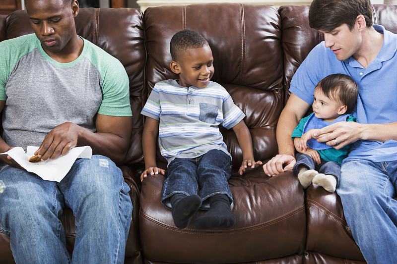 两个父亲带着小男孩坐在沙发上图片下载