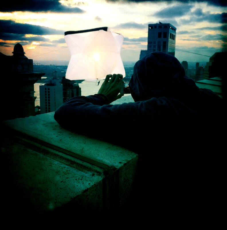 日落时，一名男子在城市屋顶拍摄气球灯图片下载