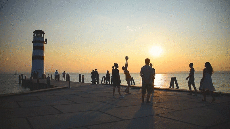 日落时分码头上玩球的人的剪影图片下载