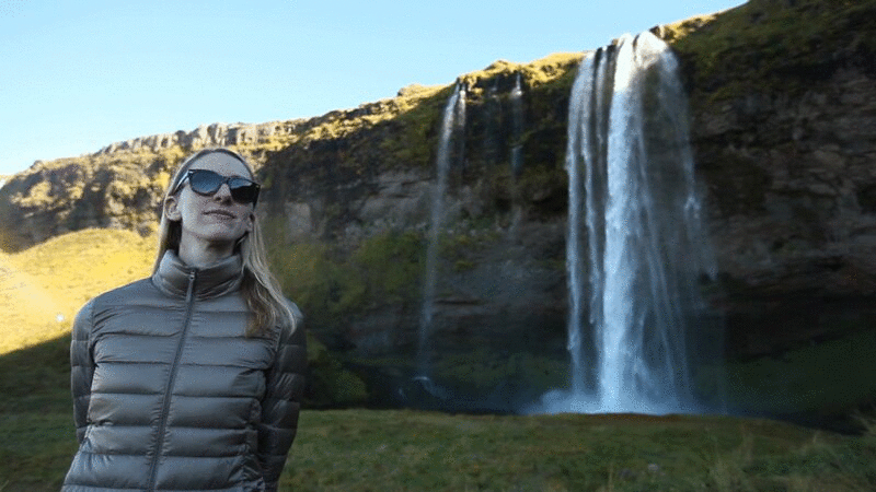 戴墨镜的女人站在瀑布附近图片下载