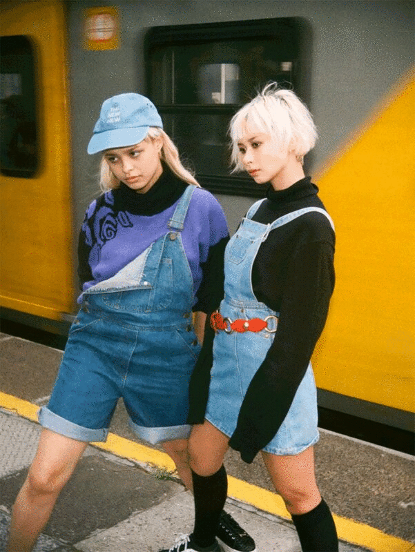 两个时尚的年轻成年妇女的肖像在短工装裤附近的火车图片下载