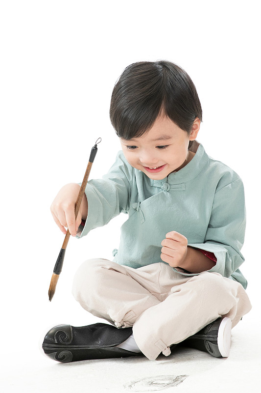 可爱的小男孩坐在地上用毛笔写字图片素材