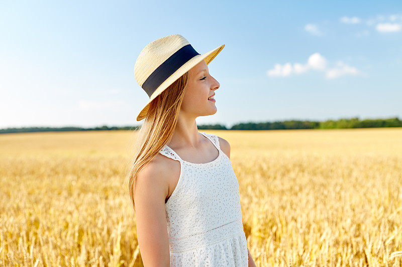 自然、时尚、人的概念——夏日麦田里戴着草帽微笑的小女孩的肖像。夏天田野上戴草帽的女孩的肖像图片下载