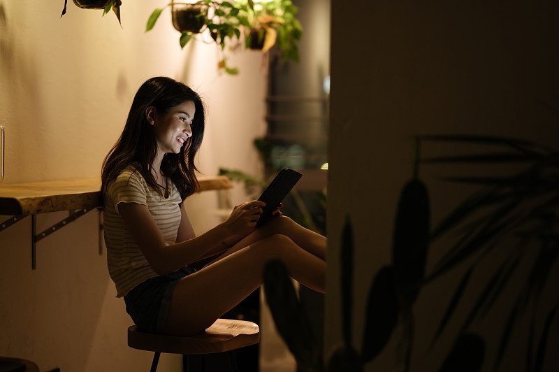 亚洲年轻女孩夜晚在家使用平板电脑图片下载