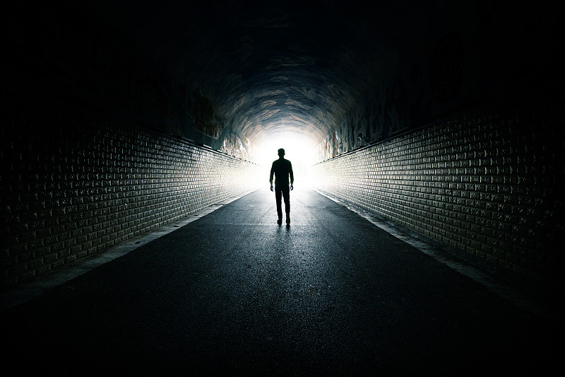 一个男人从黑暗的通道里走向光明图片素材