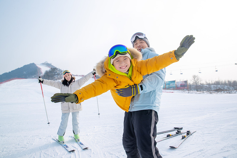 滑雪场上抱着儿子飞的父亲和滑雪的母亲图片下载