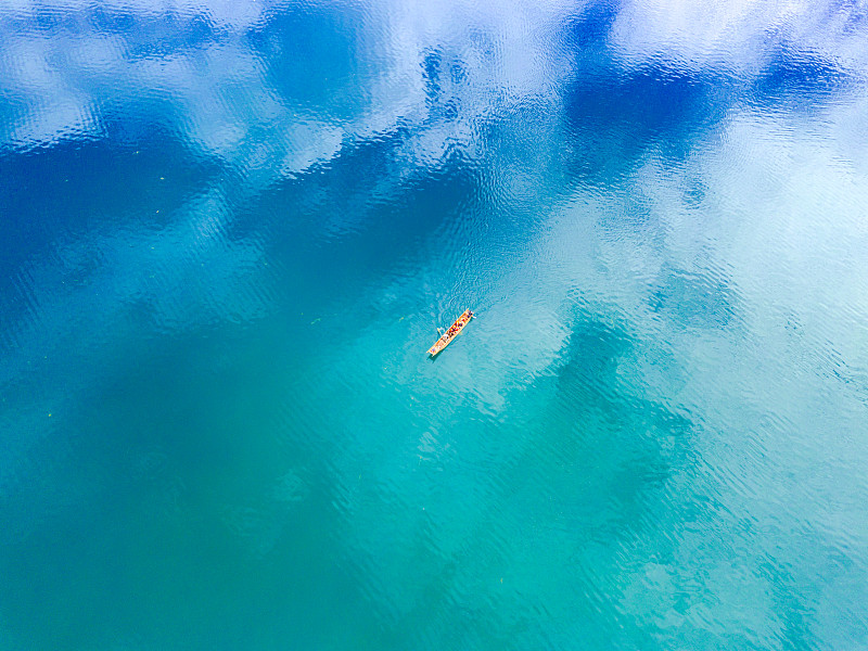 航拍蓝天白云反射下的泸沽湖面划船的人图片素材