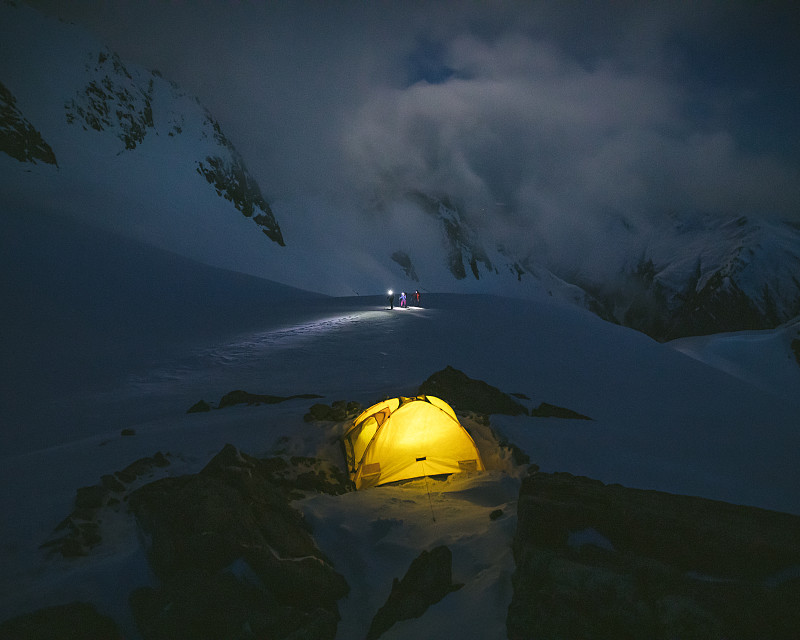 一个站在白雪皑皑的山上，顶着黄色的帐篷图片下载
