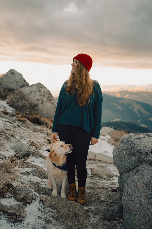 美国博伊西，一个女人和一只狗站在日落时分的山上图片素材